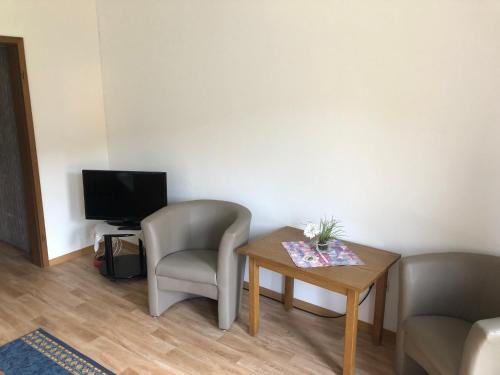 a room with a table and a chair and a television at Zum waldfrieden in Neuhof