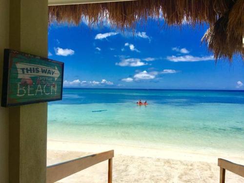a sign on a beach with a boat in the water at Tropical Fun Ta Sea Rentals in Siquijor