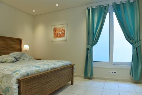 a bedroom with a bed with blue curtains and a window at Villa Gournes Resort in Porto Heli