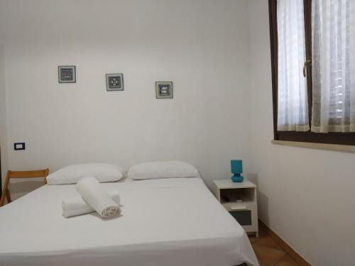 a white bed in a white room with a window at Villa Egusa in Favignana