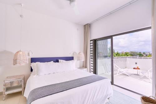 a white bedroom with a large bed and a balcony at Les Estivales Beachfront Suites & Penthouses by LOV in Trou aux Biches