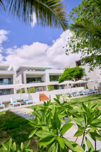 a large white building with chairs and trees at Les Estivales Beachfront Suites & Penthouses with LOV in Trou aux Biches