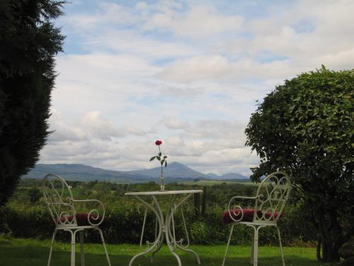 two chairs and a table with a vase on it at Lower Balwill in Buchlyvie