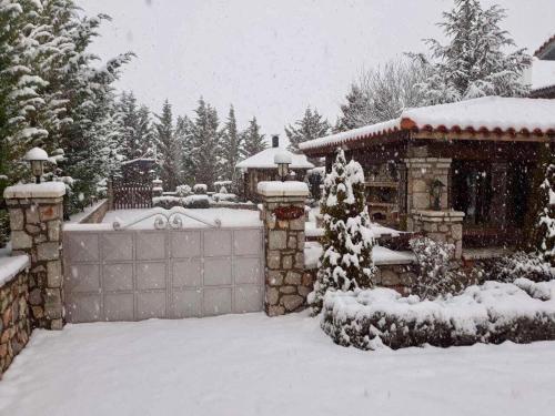 a snow covered yard with a house with a fence at villa in Parnassos in Arachova