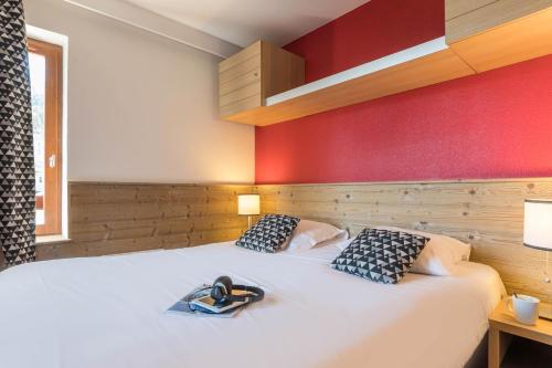 um quarto com uma cama branca e uma parede vermelha em Résidence Pierre & Vacances Le Britania em La Tania