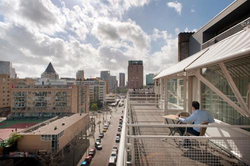 a man sitting on a balcony of a building at Leonardo Hotel Rotterdam Savoy in Rotterdam