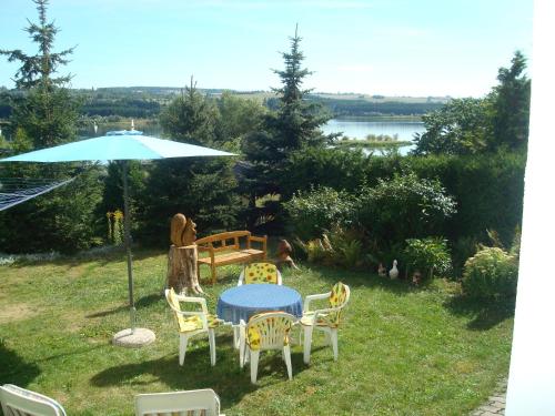 uma mesa e cadeiras e um guarda-sol na relva em Pension Seeblick em Quingenberg