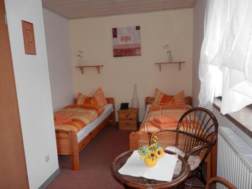 two beds in a room with a table and chairs at Pension Seeblick in Quingenberg