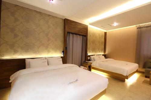 a hotel room with two beds with white sheets at Hotel Airport in Busan