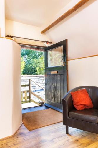 a living room with a leather couch in front of a door at Puddleduck Valley in Holsworthy