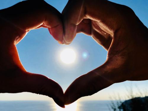 two hands forming a heart with the sun in the background at Hotel Doria in Cavi di Lavagna