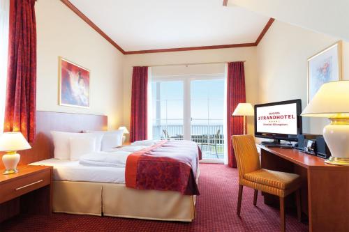 a hotel room with a bed and a desk with a computer at Morada Strandhotel Ostseebad Kühlungsborn in Kühlungsborn