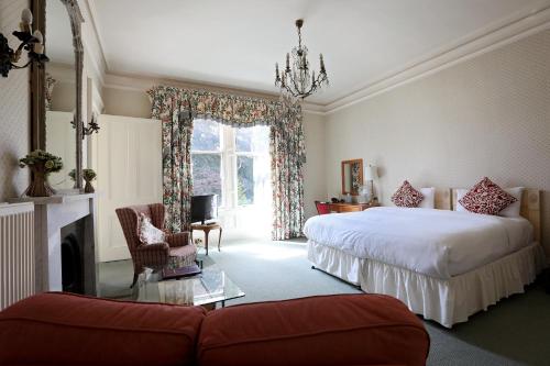 Kingsknowes Hotel في غالاشيلز: غرفة نوم بسريرين واريكة وموقد
