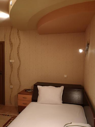 a bedroom with a white bed and a wooden headboard at Стаи за гости "Панега" in Pleven