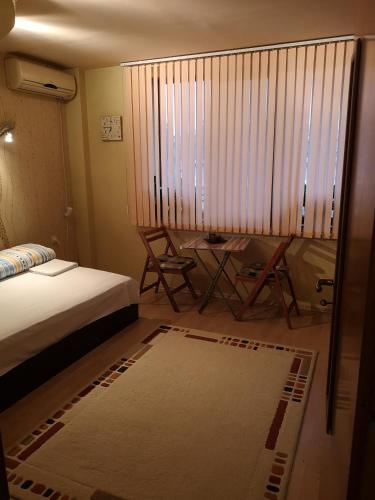 a bedroom with a bed and a table and a window at Стаи за гости "Панега" in Pleven