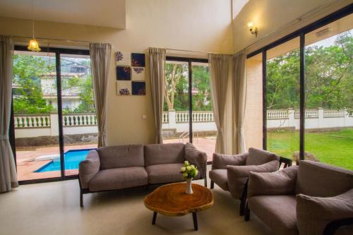 a living room with a couch and chairs and a table at StayVista's Greenwoods Villa 10 - City-Center Villa with Private Pool, Terrace, Lift & Carrom Board in Lonavala