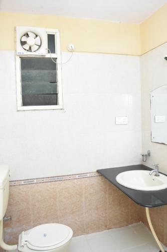 a bathroom with a sink and a toilet and a window at Hotel Surya Residency Majestic in Bengaluru