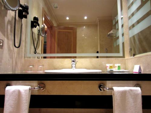 a bathroom with a sink and a mirror and towels at Gran Hotel Los Abetos in Santiago de Compostela