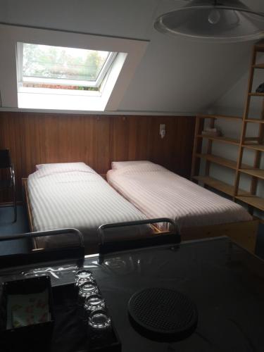 two beds in a room with a desk and a window at Cozy room in residential Alkmaar in Alkmaar