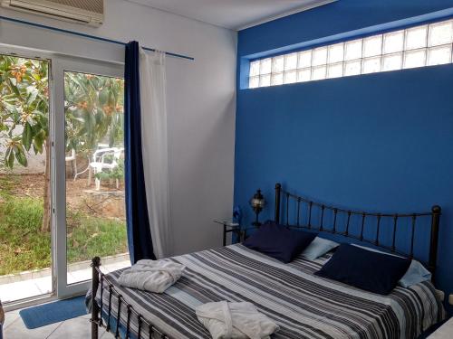 a blue bedroom with a bed and a large window at Seafarer's Suite in Galaxidi