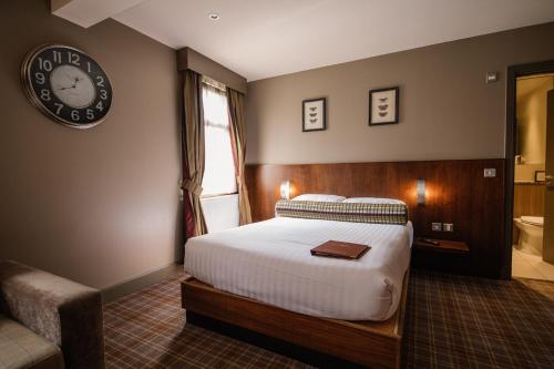a bedroom with a bed and a clock on the wall at Lynnhurst Hotel in Johnstone
