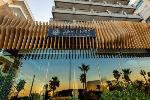 un cartel en la parte delantera de un edificio con palmeras en Coral Hotel Athens, en Atenas