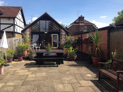 a patio with a table and some potted plants at Random Hall in Slinfold