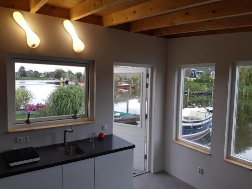 a kitchen with two large windows and a sink at Costa del Twel in Uitwellingerga