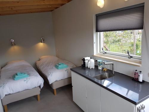 a kitchen with two beds and a sink and a window at Costa del Twel in Uitwellingerga