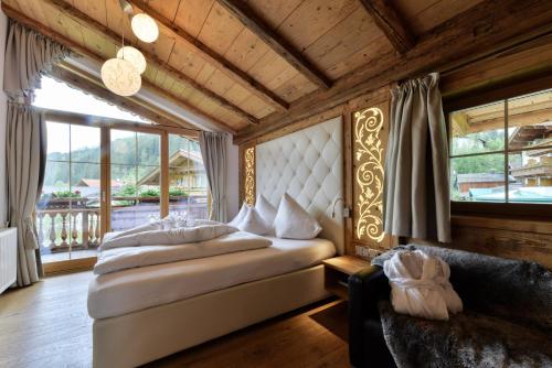 a bedroom with a bed and a large window at Oberlechtaler Hof Boutique Hotel in Holzgau