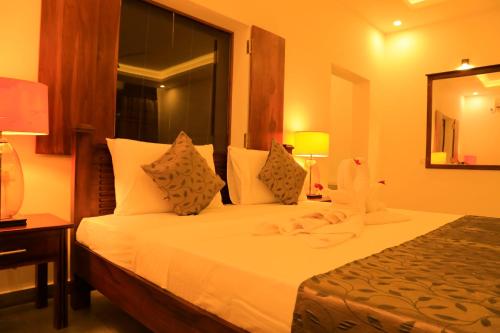 a hotel room with a bed with white sheets and pillows at Tara Watergate in Tissamaharama