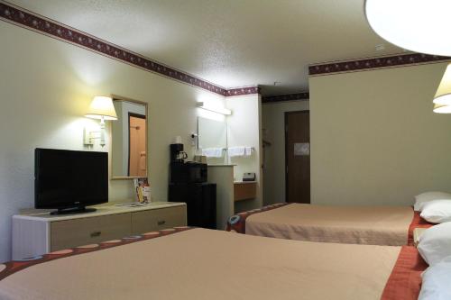 a hotel room with two beds and a flat screen tv at Super 8 by Wyndham San Antonio/Fiesta in San Antonio