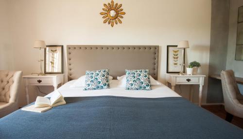 a bedroom with a large bed with blue and white pillows at Domaine Le Bois Des Dames in Chantemerle-lès-Grignan