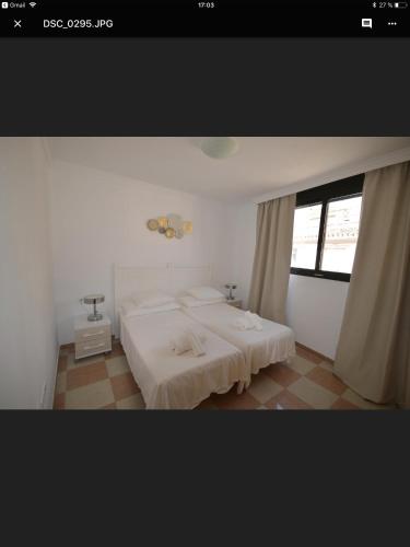 a white bedroom with two beds and a window at Calle Cinteria in Málaga