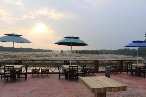 a group of tables and chairs with umbrellas at Jungle Wildlife Camp in Sauraha
