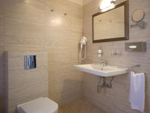 a bathroom with a sink and a toilet and a mirror at Barokk Hotel Promenád in Győr