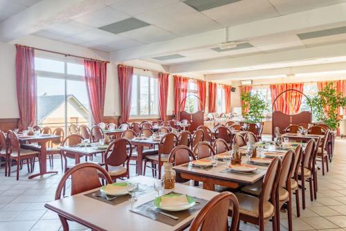 a dining room with tables and chairs and windows at Azureva Murol in Murol