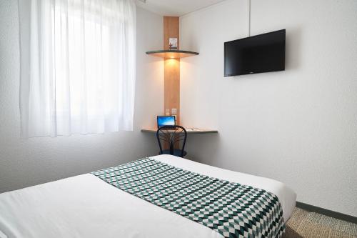 a hotel room with a bed and a television at Atena Bordeaux Sud Est Créon - Vélo Friendly in Créon