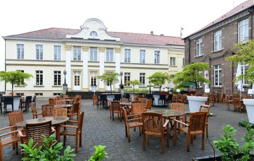 an empty patio with tables and chairs in front of a building at Schlosshotel Westerholt in Herten