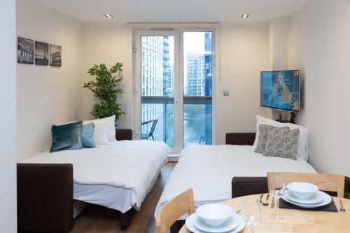 Royal Crossharbour Apartment في لندن: غرفة معيشة بسريرين وطاولة طعام