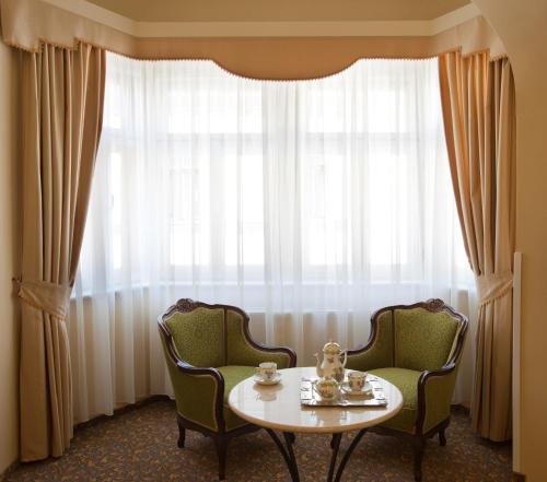 a room with two chairs and a table in front of a window at Barokk Hotel Promenád in Győr