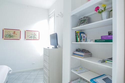a white room with white shelves and a tv at Central cosy apartment in Bologna