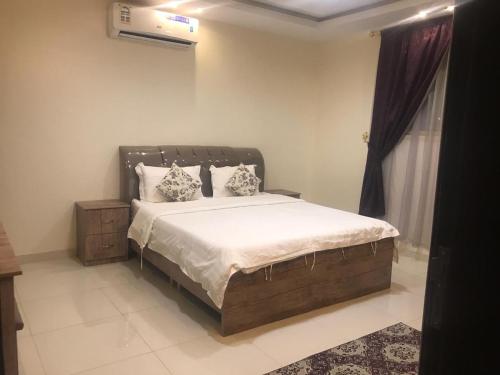 a bedroom with a large bed with white sheets and pillows at الماسة الخليج للشقق المفروشة in Buraydah
