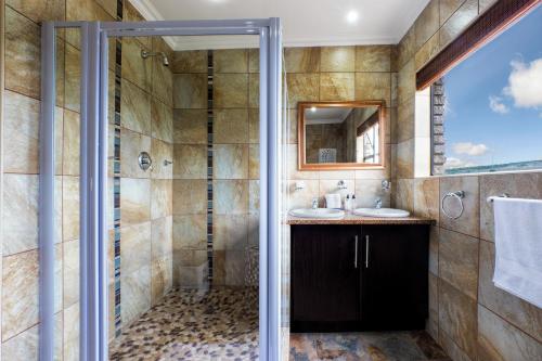 a bathroom with a shower and two sinks and a mirror at Shawheim@Hartenbos in Hartenbos