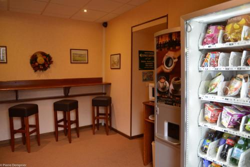 a bar with two stools next to a refrigerator at Hôtel Saint-Georges in Saint-Jean-de-Maurienne