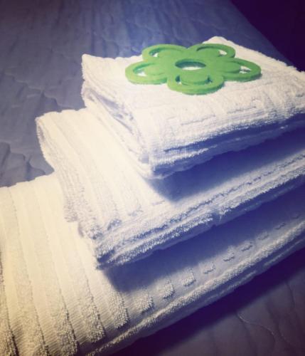 a stack of white towels with a green flower on top at La Sosta Motel Tavola Calda in Matera