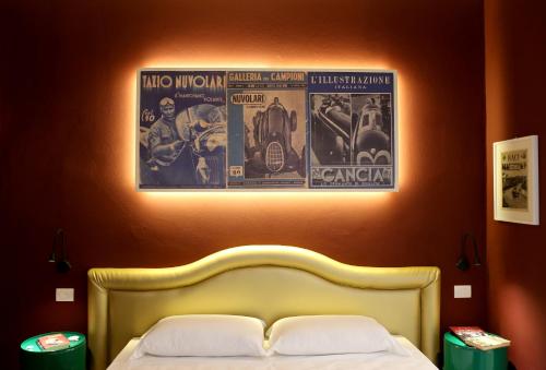 a bedroom with a bed with two posters on the wall at OFFICINA TESINI Guest Rooms Verona in Verona
