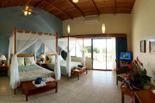 a bedroom with a canopy bed and a television in it at Cristal Ballena Boutique Hotel & Spa in Uvita