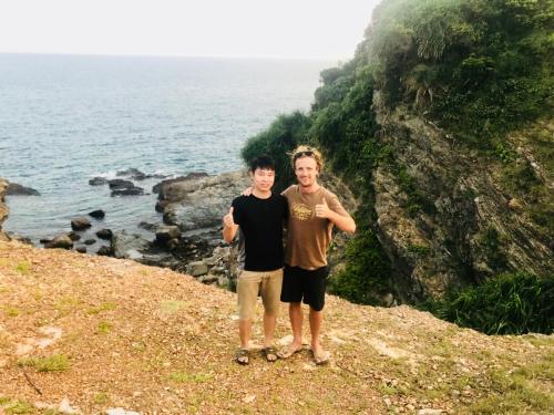 two men standing on a hill near the ocean at Coto Center Homestay in Dao Co To