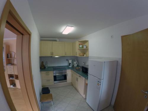 a small kitchen with a white refrigerator and cabinets at Ferienwohnung Am Berzdorfer See, Görlitz, Klein Neundorf, Seestraße in Görlitz